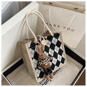 Close-up of linen tote bag with checkerboard pattern and knit bunny charm in a gift box