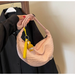 Detailed shot of pink pleated crescent bag with cute yellow duck plush charm decoration