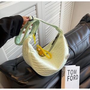 Detail of mint green pleated crescent bag with yellow cartoon bear charm and adjustable strap