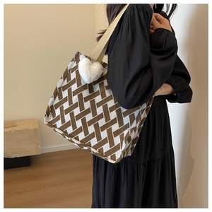Detail of a large knit tote with geometric brown patterns and a plush heart charm
