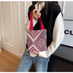 Close-up of ethnic hand-woven bucket bag featuring geometric diamond patterns and red strap