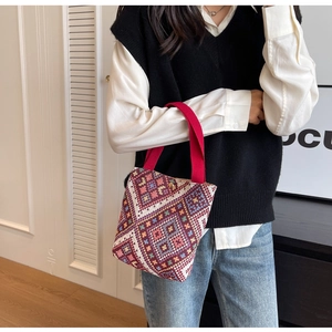Close-up of ethnic bucket bag with vintage geometric weaving and red canvas handle