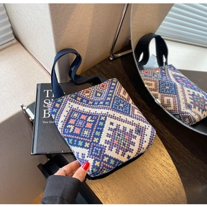 Detailed close-up of ethnic geometric pattern weaving and gold magnetic buckle on handbag