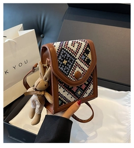 Detail of vintage crossbody bag with woven flap design and cute plush bunny charm