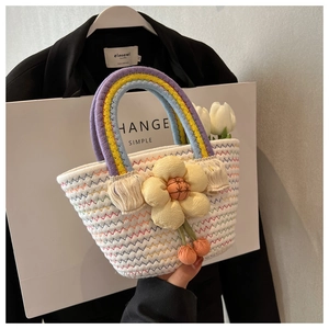 Detail of colorful woven tote bag featuring rainbow handles and decorative cream fabric flower
