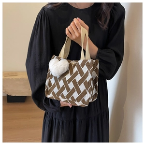 Detail of knit handbag with brown geometric pattern and white heart plush charm