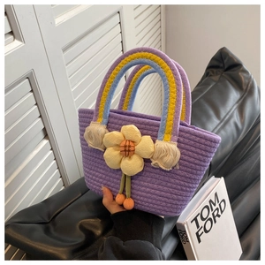 Detail of purple woven straw basket bag with rainbow handle and large yellow fabric flower