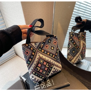 Close-up of ethnic knit bucket bag with colorful geometric patterns and gold button