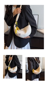 Detailed view of white pleated crescent bag with yellow duck charm on wide shoulder strap
