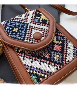 Close-up of ethnic woven crossbody bag with geometric patterns and brown leather trim