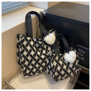 Detail of black and white woven canvas tote bags with heart plush charms on glass shelf