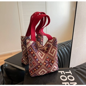 Detail of bohemian geometric woven tote bag with red canvas handle on leather background