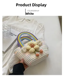 Detail of woven straw handbag with rainbow handle and floral charms on white dress
