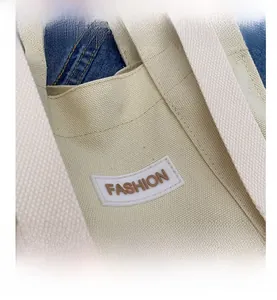 Detail shot of the ivory canvas bag handle and the stitched Fashion patch logo