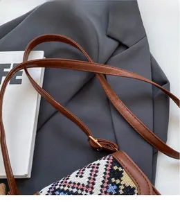 Detail of adjustable brown leather strap and geometric pattern on stylish crossbody bag