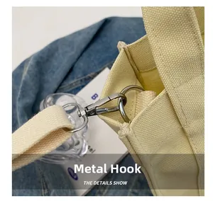Detail view of the silver metal hook and strap connector on a beige canvas tote bag