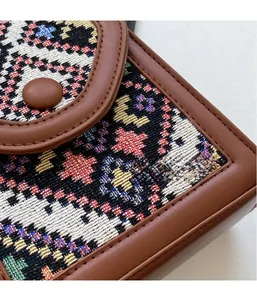 Detail of bohemian jacquard fabric crossbody bag with brown leather trim and metal clasp
