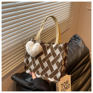 Close-up of geometric woven tote bag with heart pendant and metal snap closure