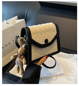 Détail d'un mini sac bandoulière chic monochrome avec un joli pendentif lapin en peluche