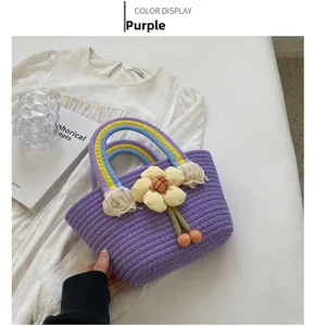 Detail of purple woven cotton handbag with floral decor and colorful braided handle