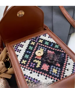 Detail of the golden metal snap closure and colorful embroidery on a vintage crossbody bag