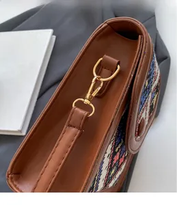 Detail of premium golden metal hook and textured leather stitching on a crossbody bag