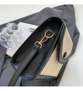 Détail d'un sac bandoulière bicolore chic avec ferrures dorées et coutures ondulées