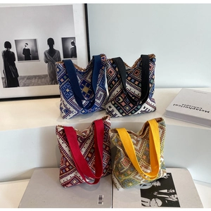 Detail view of woven ethnic tote bags in four colors on a minimalist display