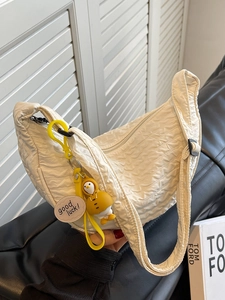 Chic beige pleated crescent hobo bag with a cute yellow duck charm and adjustable strap