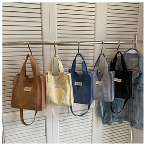 Detailed row of multi-colored canvas crossbody bags with adjustable straps on a rack