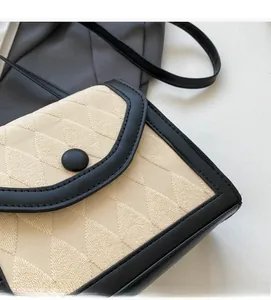 Détail du sac bandoulière matelassé beige avec bordure en cuir noir et bouton pression