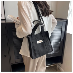 Side view of a black canvas crossbody bag styled with a white shirt in a modern interior