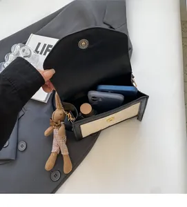 Vue intérieure d'un petit sac bandoulière avec espace pour deux smartphones et parfum