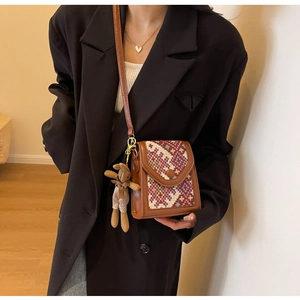 Detail view of a vintage crossbody bag with woven flap and brown bunny charm on a model