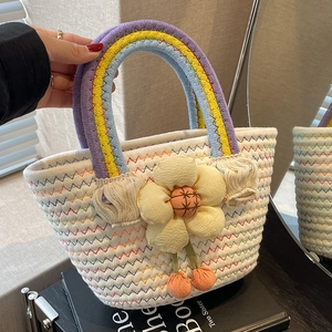 Handwoven basket bag with rainbow handles, colorful wave patterns and a floral detail