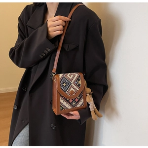Detail view of ethnic crochet pattern on brown leather crossbody bag with small bear charm