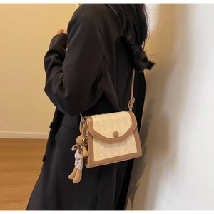 Détail d'un sac à bandoulière matelassé crème avec garniture en cuir marron et ours