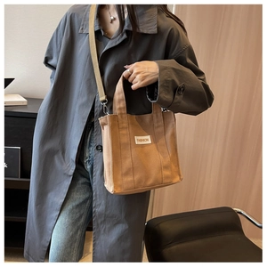 Close-up of khaki canvas tote bag with fashion label shown on a stylish model
