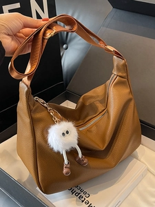 Brown litchi leather hobo bag with wide strap and cute plush monster charm detail