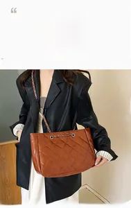 Brown quilted tote bag with chain shoulder strap shown as worn by model