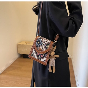Detail view of a retro geometric woven crossbody bag with a cute plush bunny pendant