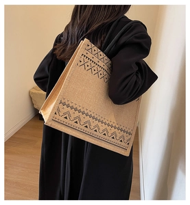 Detailed view of a large linen tote bag with ethnic geometric patterns on a model