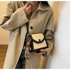 Détail du sac bandoulière en tricot avec bordure en cuir noir et breloque lapin