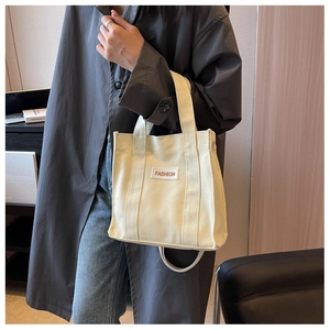 Detail of beige canvas crossbody bag with Fashion patch and comfortable double handles