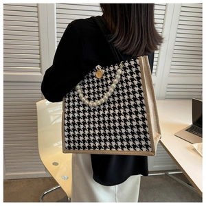 Detail of houndstooth tote bag featuring elegant pearl handles and vintage button accent