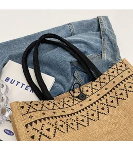 Detail of burlap tote bag with ethnic pattern and thick black rope handles