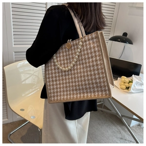 Detail of houndstooth tote bag featuring elegant pearl handle and wooden button accent