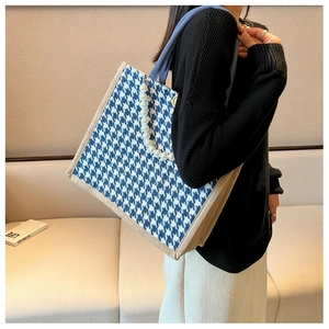Detail of blue and white houndstooth tote bag with pearl chain and beige canvas straps