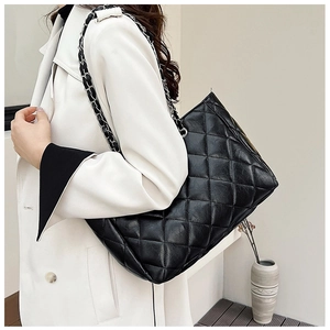 Close-up of black quilted leather tote bag with silver chain strap and refined stitching