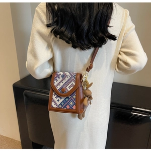 Detail of vintage woven crossbody bag with brown leather trim and cute bunny charm